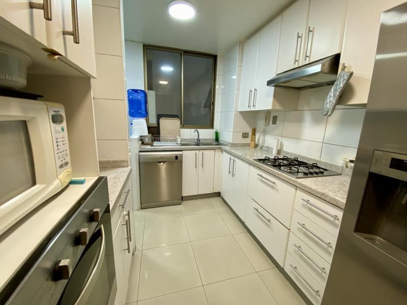 Otro ángulo de la cocina, con lavavajillas, microondas y ventana al exterior.