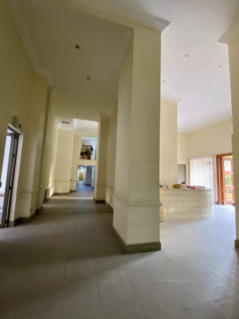Hall de acceso del edificio, con columnas, conserjería y salida al jardín interior.