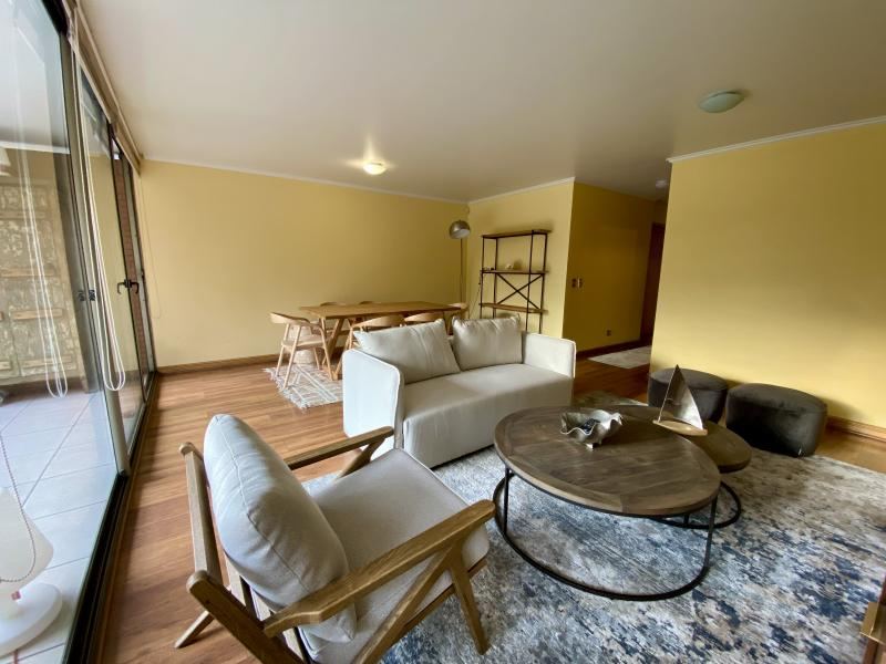 Estar del living con sofás, mesa de centro y salida directa a la terraza por el ventanal corrido.